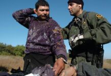 agente de la Patrulla Fronteriza mientras registra a un emigrante indocumentado que fue detenido intentando cruzar a Estados Unidos
