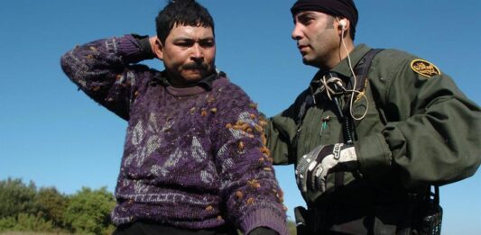agente de la Patrulla Fronteriza mientras registra a un emigrante indocumentado que fue detenido intentando cruzar a Estados Unidos