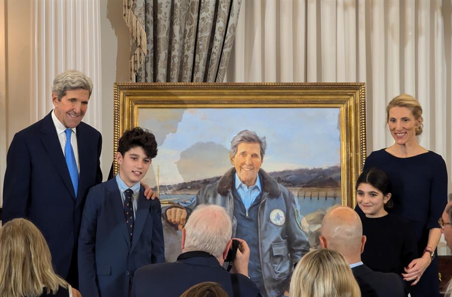 El exsecretario de Estado de Estados Unidos John Kerry (i) posa con su familia junto a su retrato oficial