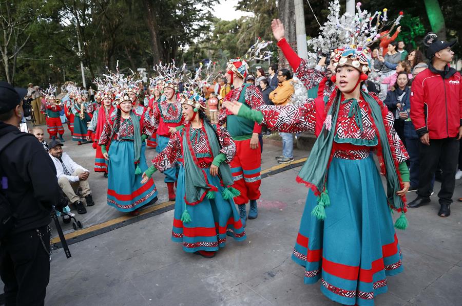 Integrantes de una comparsa bailan música navideña durante el primer día de novenas este lunes, en Bogotá