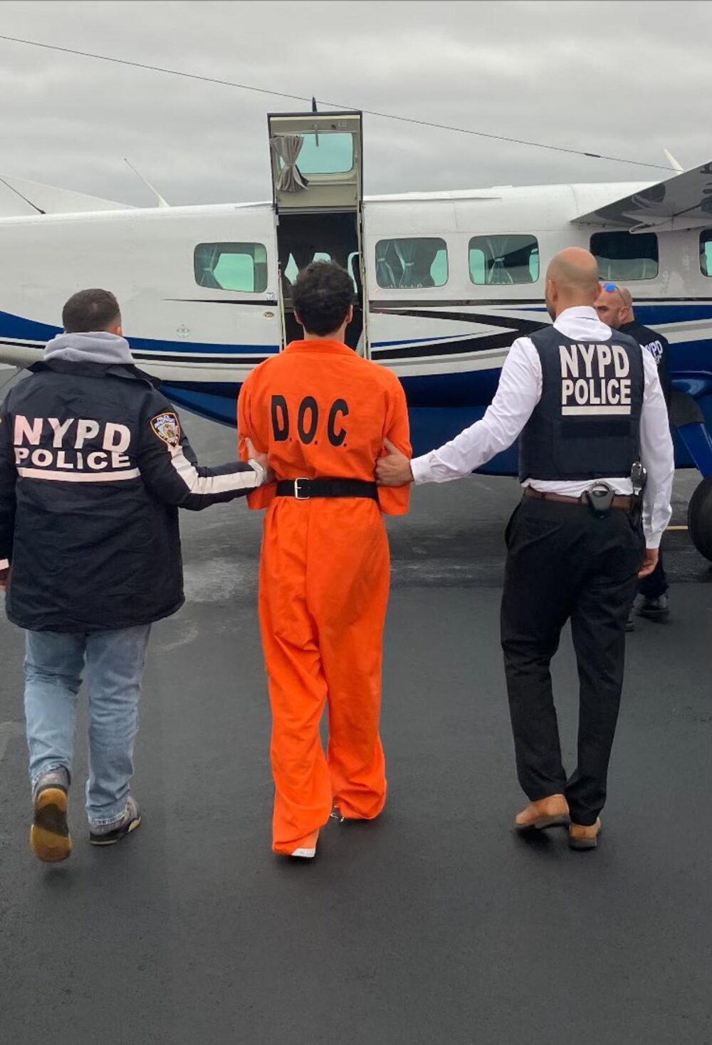 Luigi Mangione siendo trasladado por agentes a un avi&oacute;n con destino a Nueva York