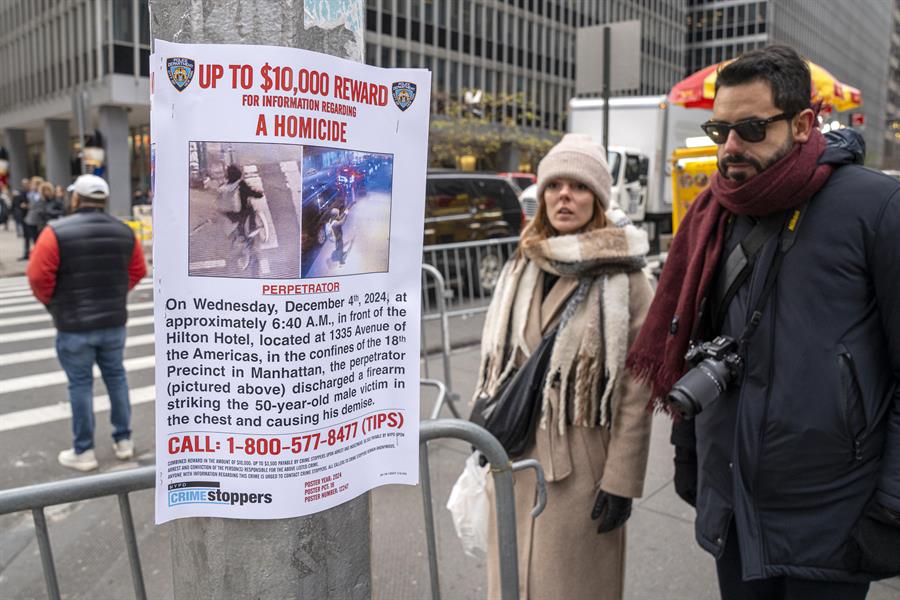Personas leen un cartel de recompensa para quien ayude en la captura del asesino del director ejecutivo