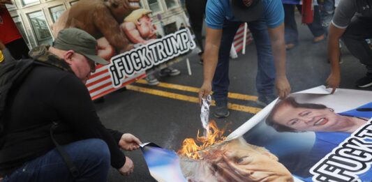 Personas queman carteles con la imagen de Donald Trump durante una manifestación frente a la Embajada de Estados Unidos