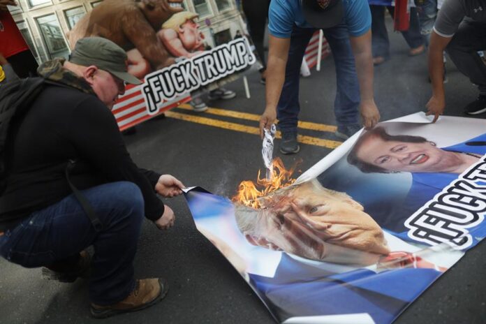 Personas queman carteles con la imagen de Donald Trump durante una manifestación frente a la Embajada de Estados Unidos