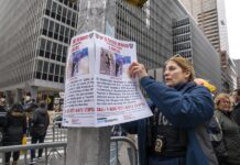 Una agente del Departamento de Policía de Nueva York (NYPD) cuelga un cartel de recompensa (2)