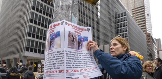 Una agente del Departamento de Policía de Nueva York (NYPD) cuelga un cartel de recompensa (2)