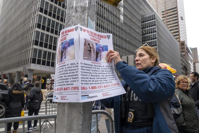 Una agente del Departamento de Policía de Nueva York (NYPD) cuelga un cartel de recompensa (2) Una agente del Departamento de Policía de Nueva York (NYPD) cuelga un cartel de recompensa (2)