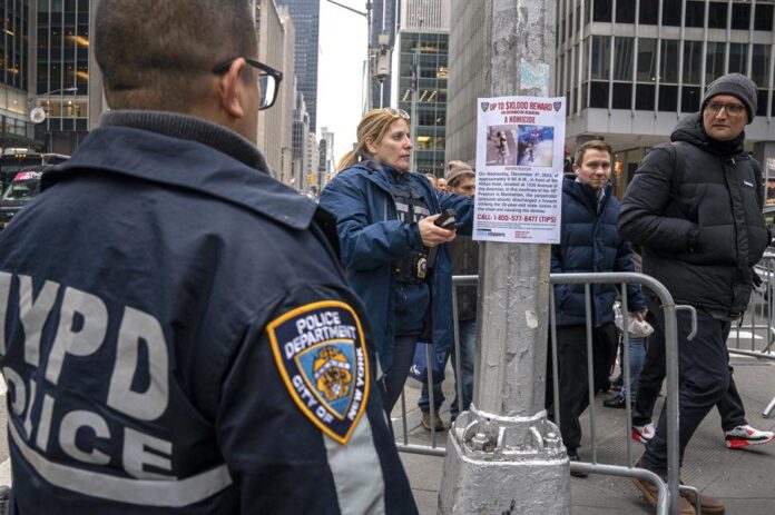 Una agente del Departamento de Policía de Nueva York (NYPD) cuelga un cartel de recompensa