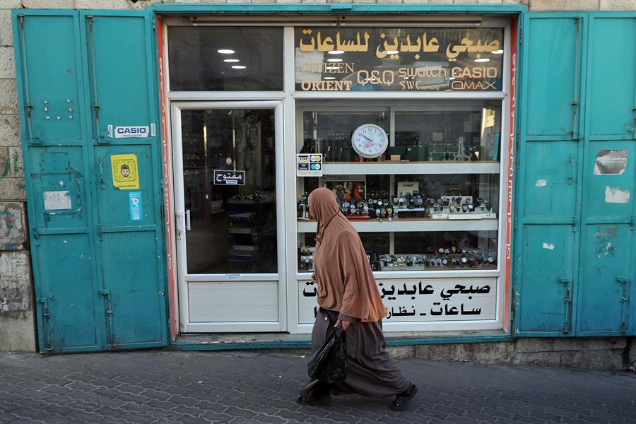 Una mujer pasa delante de una tienda de relojes en la ciudad de Bel&eacute;n, en Cisjordania ocupada