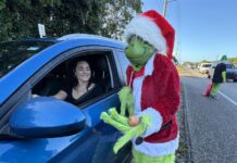 disfrazado de 'Grinch', el malvado duende verde navideño, ofreciendo una cebolla a una conductora