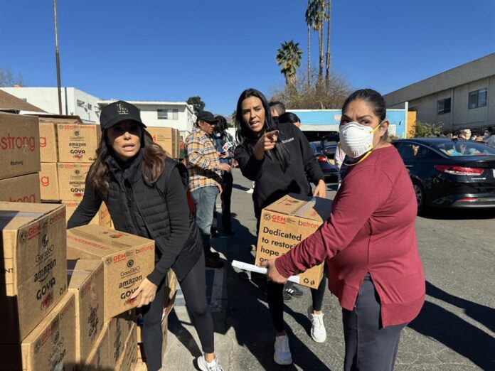 Eva Longoria (i), cargando junto a unas voluntarias unas cajas de ayuda para los afectados por los incendios