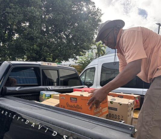 Leonard Phophil carga a un vehículo alimentos que le donan para entregar a los inmigrantes este lunes, en San Juan