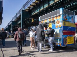 Personas consumen alimentos en un puesto de comida callejera este miércoles, en Queens Nueva York