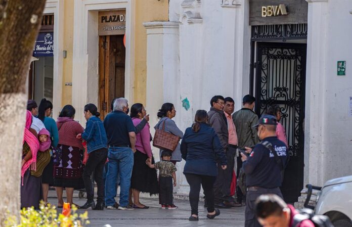 Personas hacen fila en una institución bancaria Personas hacen fila en una institución bancaria