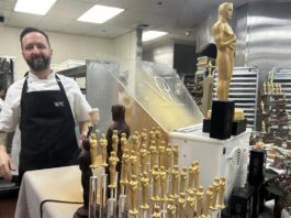 Un ayudante de cocina posa junto a figuras de chocolate de la estatuilla de los premios Oscar
