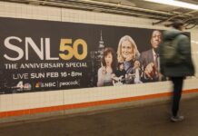 Una persona camina frente a un anuncio conmemorativo del especial del 50 aniversario del programa Saturday Night Live