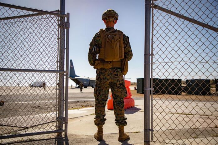 integrante del servicio militar estadounidense custodiando la entrada como parte de la Operación Guardia Sur en la Estación Naval de la Bahía de Guantánamo