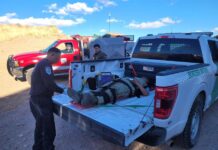 un agente mientras atiende a una mujer migrante que fue empujada por 'coyotes' en el muro fronterizo