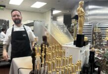 Un ayudante de cocina posa junto a figuras de chocolate de la estatuilla de los premios Oscar