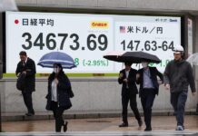 Peatones pasan junto a un panel electrónico de la bolsa que muestra el índice Nikkei de Japón