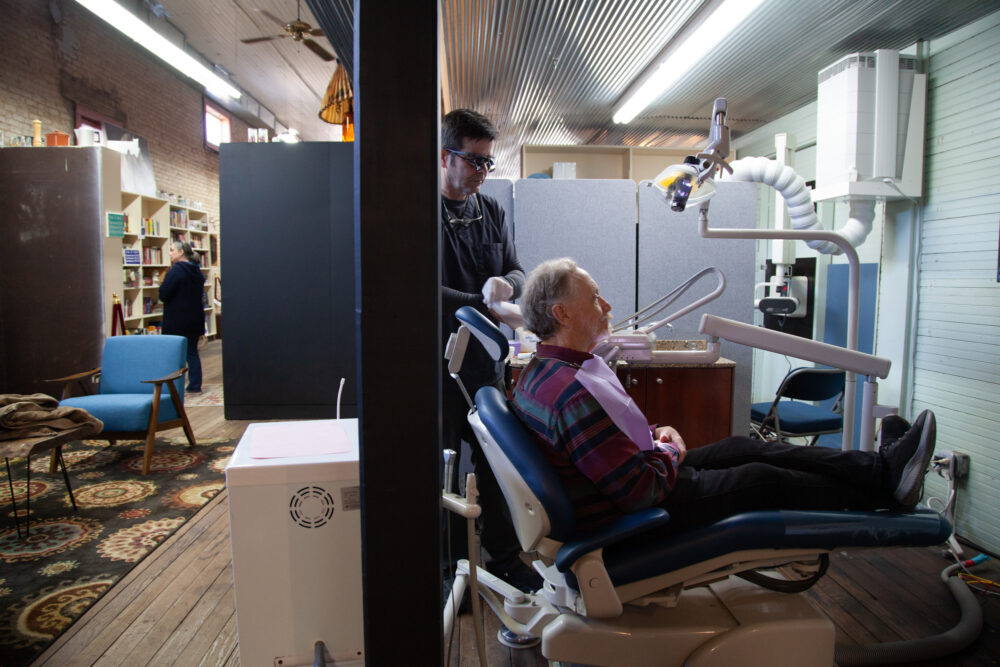 David Potts is treated by James Flanagin, the only dentist in Leslie, Arkansas, who operates out of a small clinic in the back of an antique store. About 25 million Americans live in dentist shortage areas, according to new research from Harvard University. (Katie Adkins for KFF Health News)
