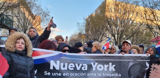 Un grupo de personas sostiene un cartel durante una vigilia por las victimas del accidente en una discoteca de Santo Domingo