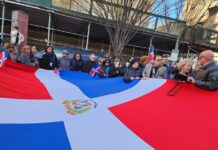 Un grupo de personas sostiene una bandera de República Dominicana durante una vigilia por las victimas del accidente en una discoteca de Santo Domingo