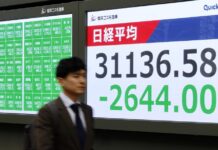 Trump pide recortar los tipos de interés y arremete contra China a la que llama "abusador" Un hombre camina junto al indicador (el Nikkei) de la Bolsa de Tokio, Japón
