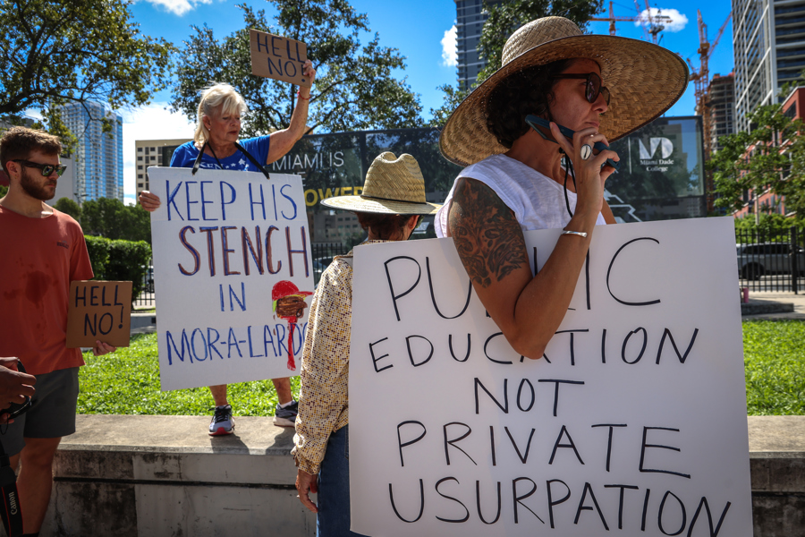 Personas muestran carteles durante una protesta contra la construcción de la biblioteca presidencial de Donald Trump este lunes, en Miami