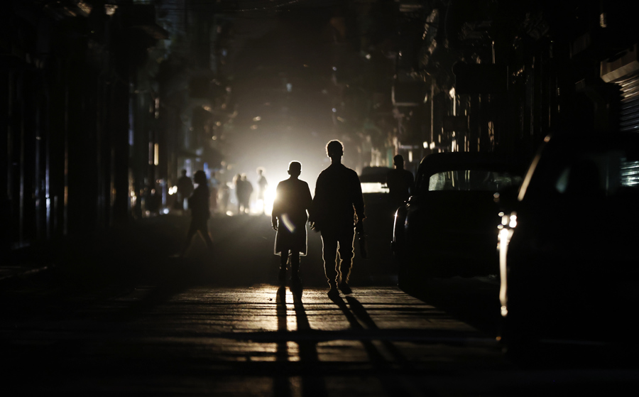 Personas caminan por una calle sin electricidad este s&aacute;bado, en La Habana