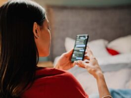 Young hispanic woman using cellphone while sitting on chair at h