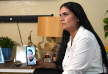 Igrayne Ribot Hernández sostiene un teléfono durante una entrevista por video a su esposo,Carlos Rodríguez