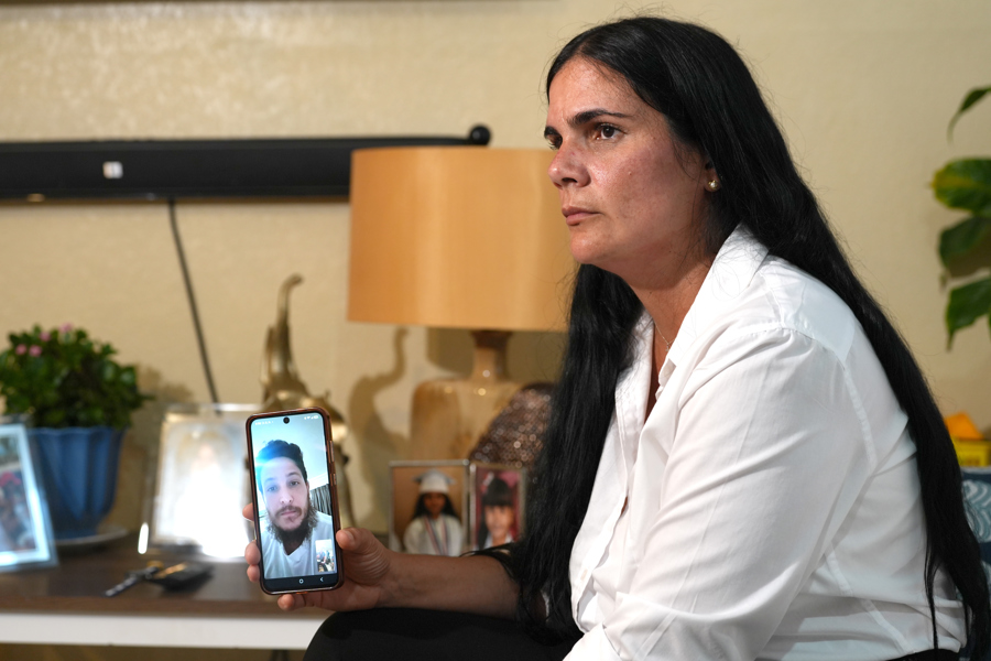 Igrayne Ribot Hernández sostiene un teléfono durante una entrevista por video a su esposo,Carlos Rodríguez