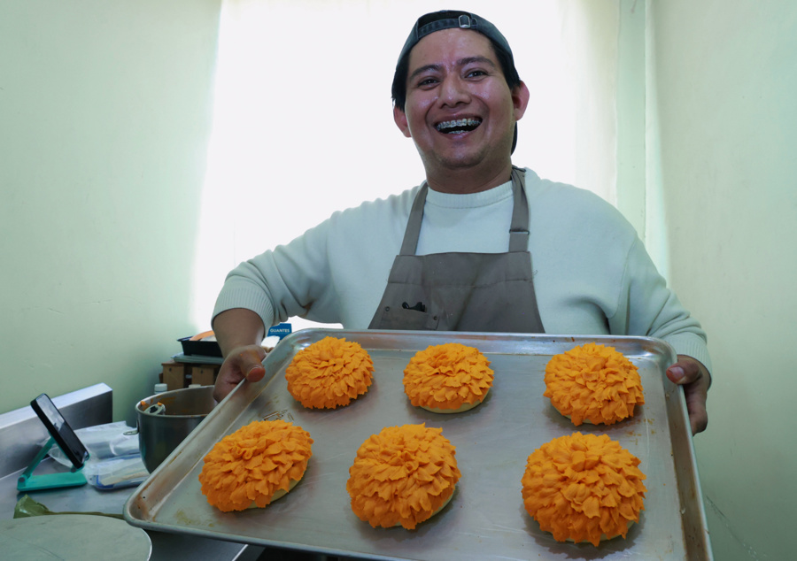 El repostero Jonathan Barrera posa con alimentos en forma de flor de cempasúchil